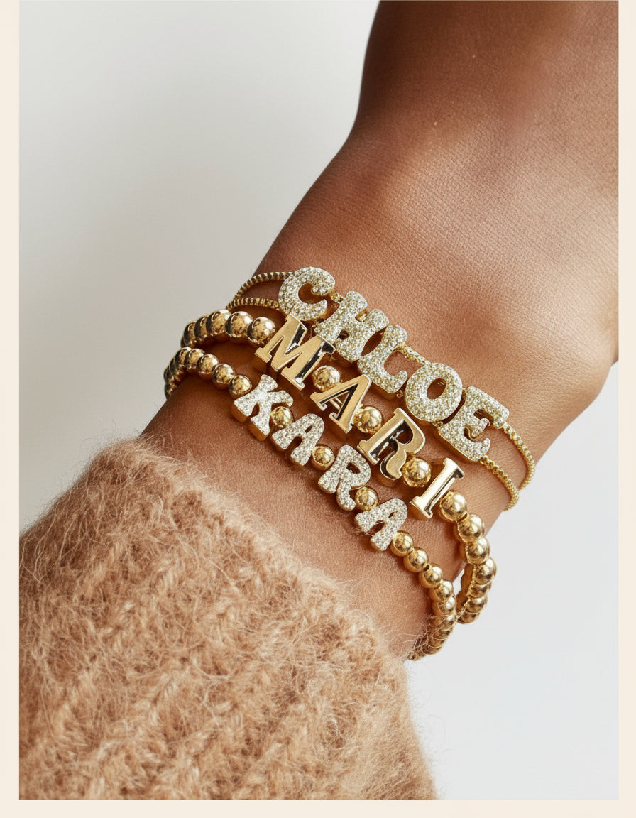 Gold bracelets with names on a wrist against a blurred background